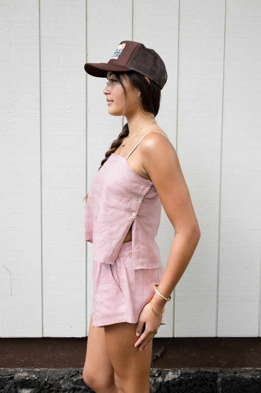 Woman wearing the Coconut Ave Montego Top in Rosey, shown in a side profile highlighting the relaxed linen silhouette and adjustable spaghetti straps.