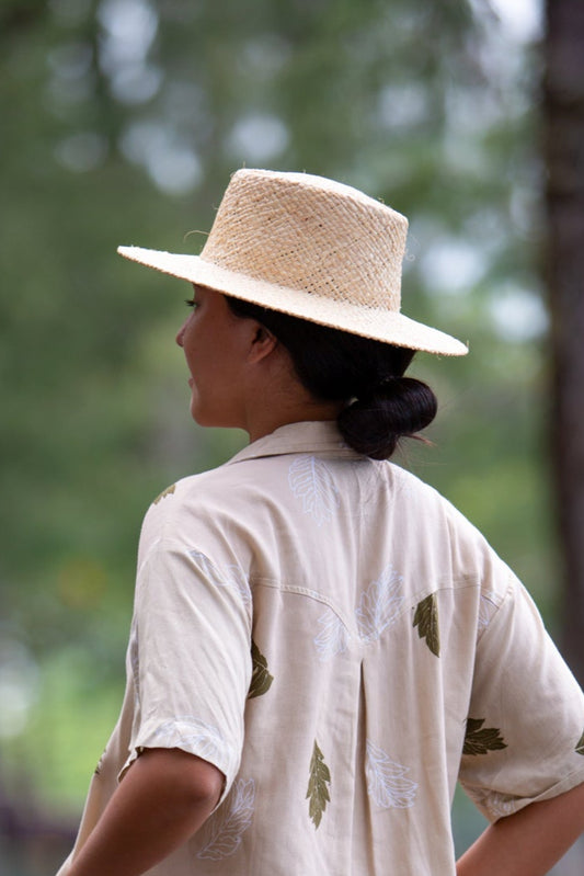 Model wearing the Coconut Ave handwoven raffia Panama hat from the back outdoors.
