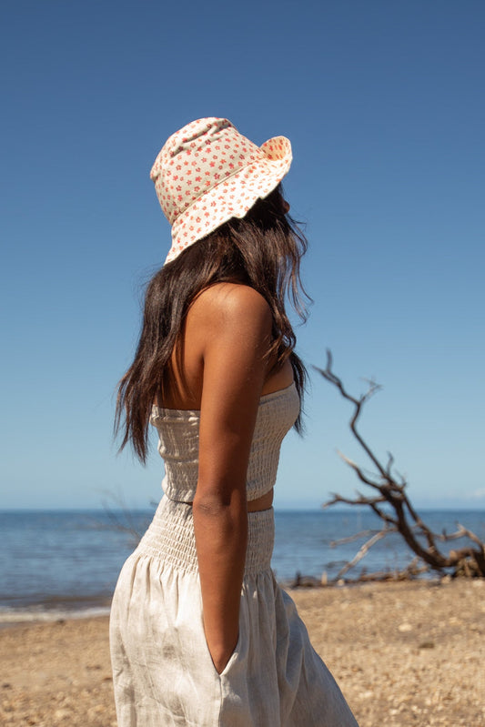 Side view of a woman wearing the Coconut Ave Sunny Days Hat in Pua Hou floral print, showcasing the lightweight 100% cotton bucket hat during a beach outing.