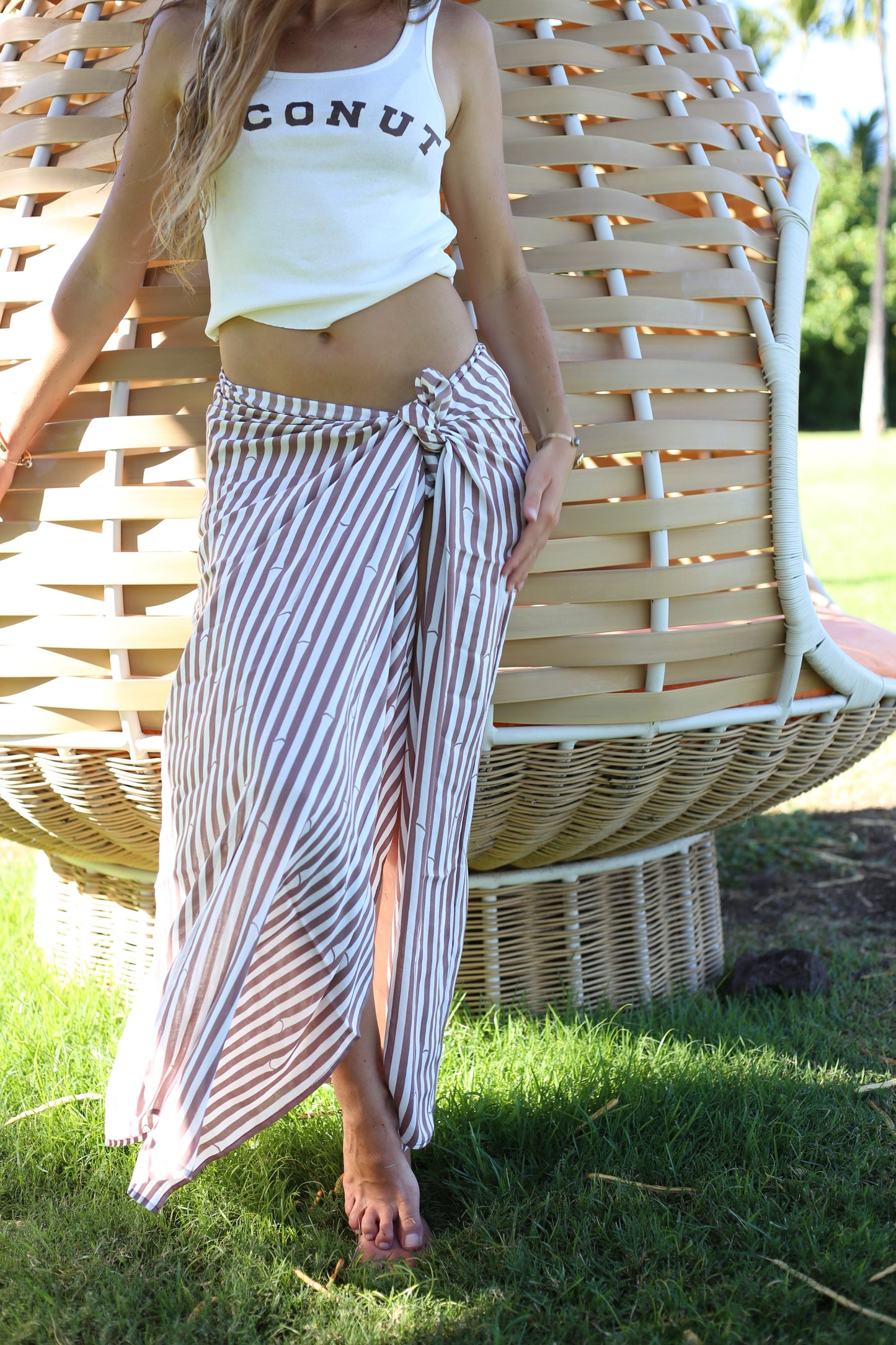 Model wearing Coconut Ave Bamboo Chocolate pareo styled as a lightweight beach cover-up with bamboo stripe tropical print.