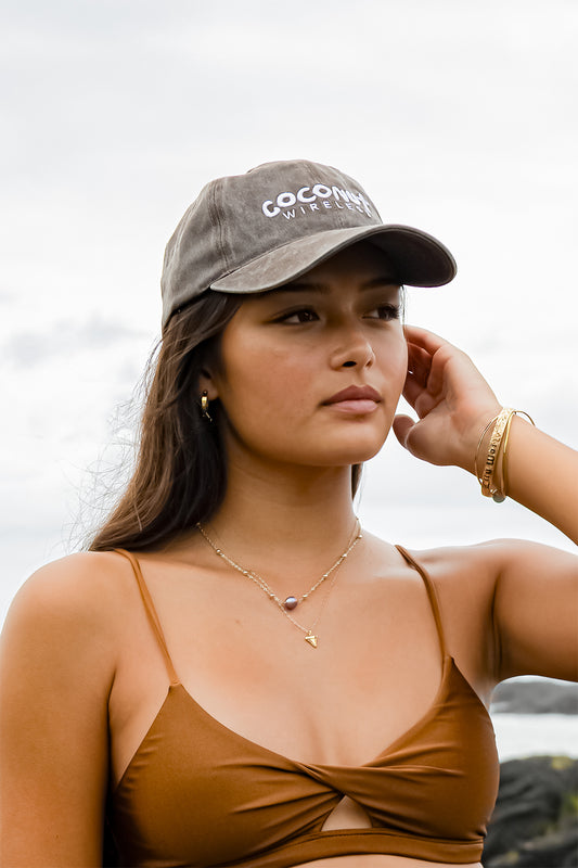 Woman wearing the Coconut Ave Dad Hat in Coconut Wireless Vintage Black featuring an embroidered Coconut Wireless logo, vintage washed cotton fabric, and adjustable baseball cap design.