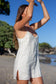 Model wearing the Coconut Ave Day Tripper Dress in Bamboo with arms raised, showcasing the lightweight linen fabric.