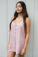 Model wearing the Coconut Ave Day Tripper Dress in Rosey, a sleeveless linen mini dress with adjustable straps and a mother-of-pearl button placket.