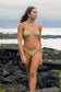Woman walking along the shoreline wearing the Coconut Ave Hula Triangle Top in the Moray print, showcasing the flattering triangle bikini design, adjustable straps, recycled stretch fabric, and tropical-inspired green and yellow pattern for beach vacations and island resort wear.