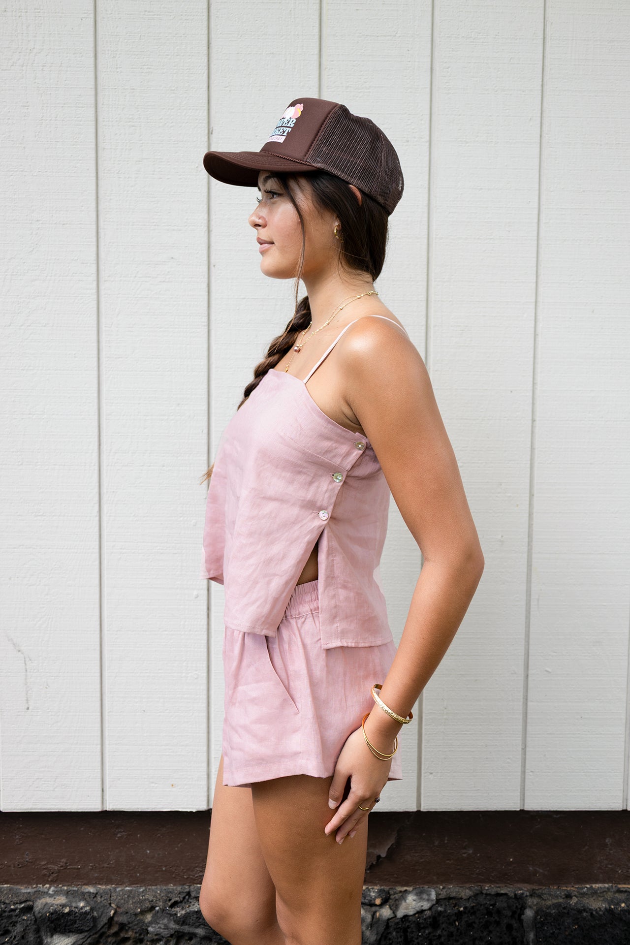 Woman wearing the Coconut Ave Montego Top in Rosey, shown in a side profile highlighting the relaxed linen silhouette and adjustable spaghetti straps.