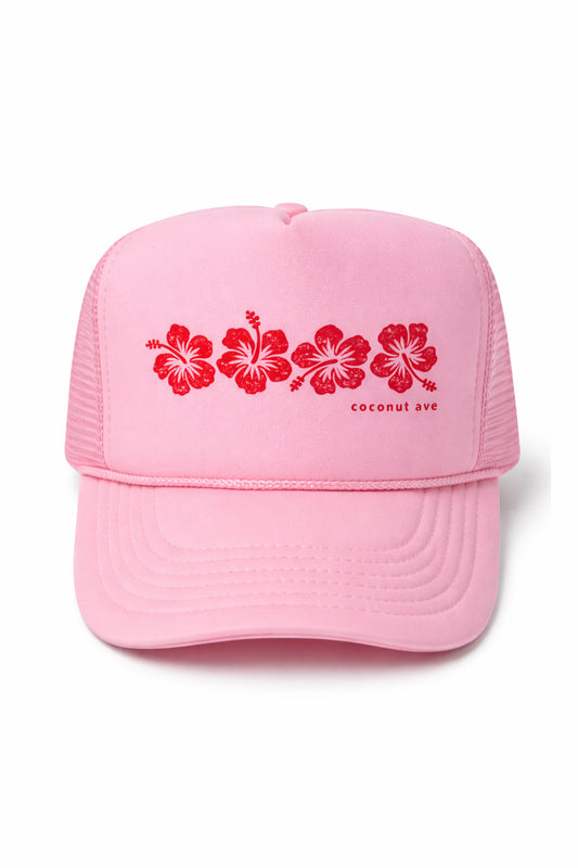 Front view of the Coconut Ave Trucker Hat – Red Hibiscus featuring a pink foam front panel with embroidered red hibiscus flowers, curved brim, white mesh back, and adjustable snapback closure.