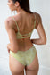 Back view of a woman wearing the Coconut Ave Half Scrunch Bottom in the Moray print, showcasing the flattering half scrunch back detail, medium coverage, seamless construction, supportive wide waistband, and green and yellow tropical-inspired pattern designed for women's swimwear, beach vacations, and resort wear.