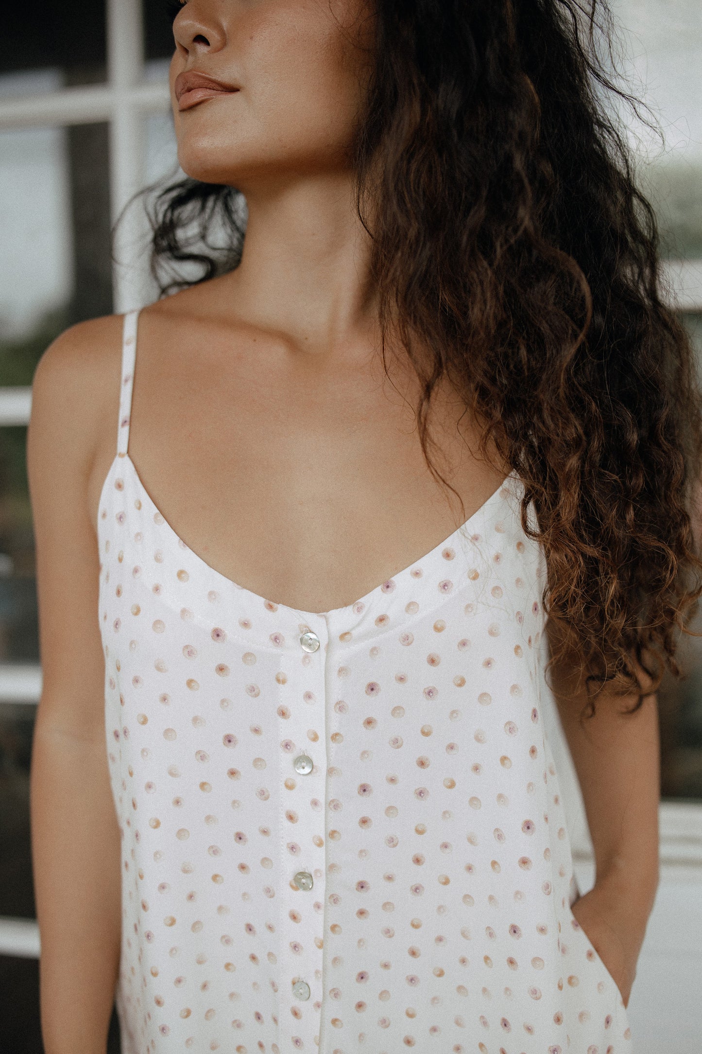 Close-up of the Puka Shell Day Tripper Dress showing its printed fabric, adjustable straps, and button-front detail.