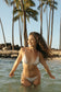 Hula Triangle Top in Hulali worn with matching swimwear while standing in the ocean