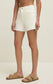 Front view of the Jonah Mid-Rise Short in Cloud showing the mid-rise waistband, zip fly, button closure, and raw hem.