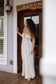 Mau'umae Maxi Dress in Puka Shell styled with sandals for relaxed resort wear on a tropical porch.
