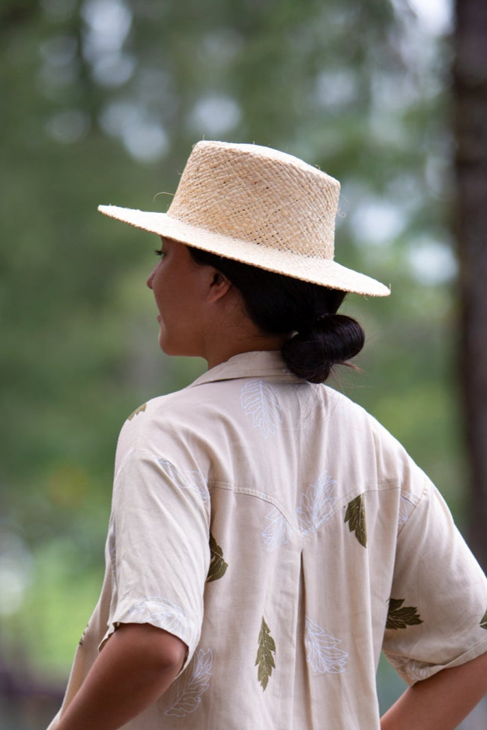 Model wearing the Coconut Ave handwoven raffia Panama hat from the back outdoors.