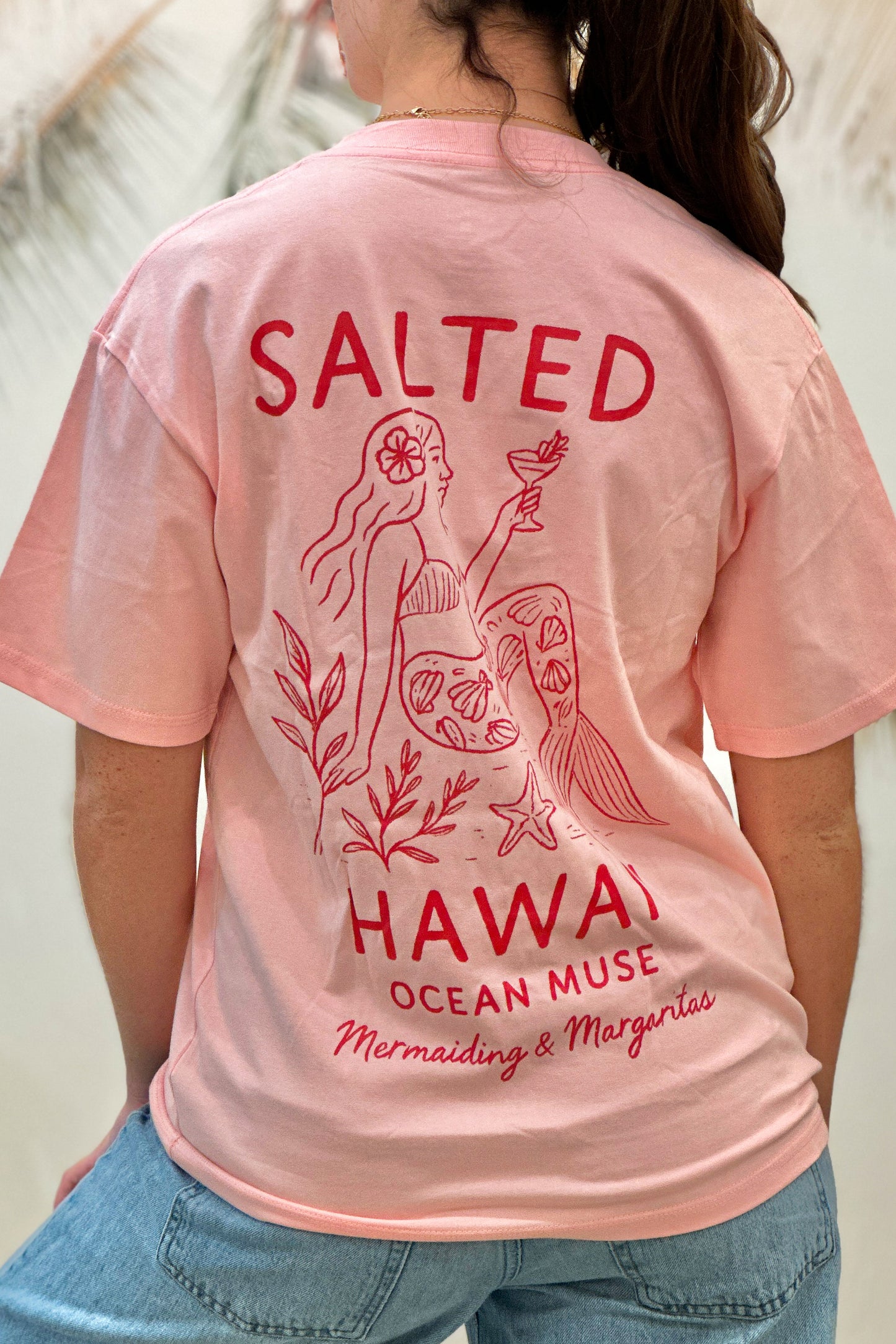 Pink t-shirt with red graphics and text on a person wearing it.