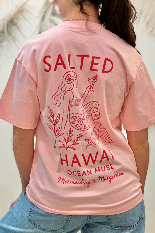 Pink t-shirt with red graphics and text on a person wearing it.