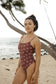 Woman wearing the Chocolate Bloom Stevie One Piece Swimsuit while posing on the beach